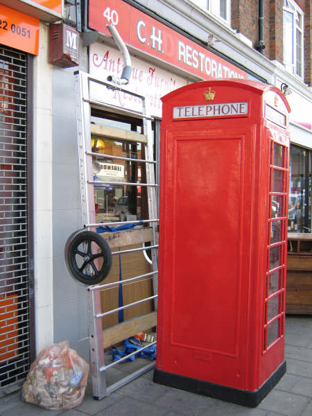 the phone booth along with the trailer parked against a wall