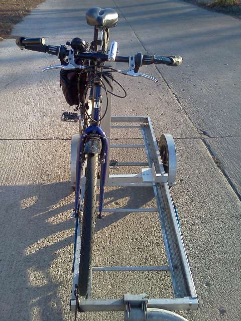 end view of a bicycle on a 64A Bikes At Work trailer, held in place using the plywood rack accessory.  The bike is offset to the left on the trailer.