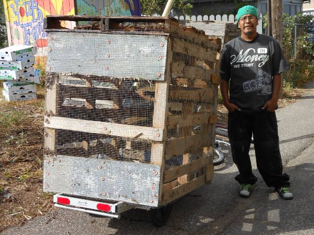 The Compostadores moving a compot bin with one of their trailers