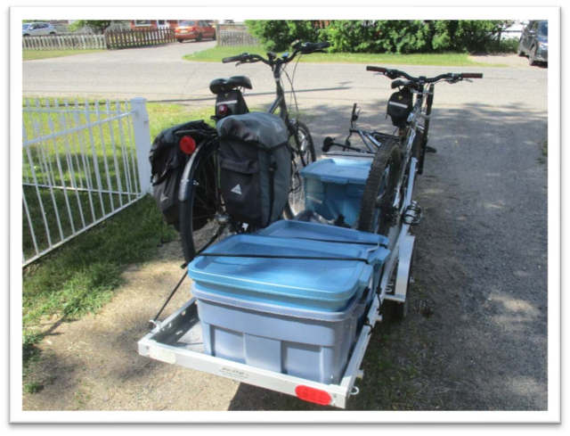 trailer loaded with three plastic bins and two bikes fastened to bike racks