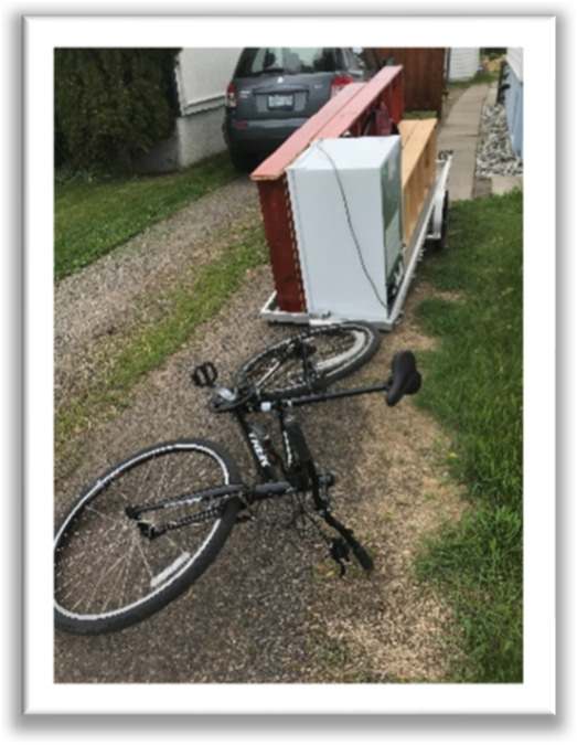 bike parked with trailer loaded with small refrigerator and book cases