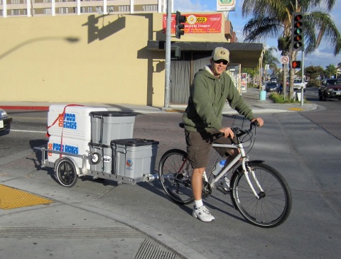 Loaded Food Rider bike trailer with dolly mounted on the side of the frame
