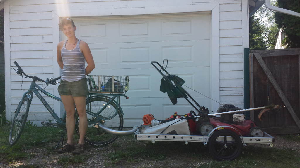 Nadia Berg standing beside her bicycle and Bikes At Work 64AW trailer loaded with landscaping equipment