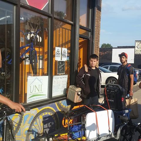 photo of UNI members standing in front of shop with loaded bicycle trailer